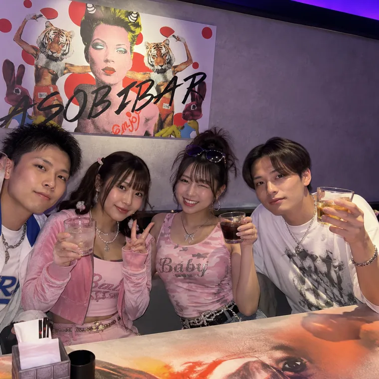 ASOBIBARのサインの前でカメラに向かう4人